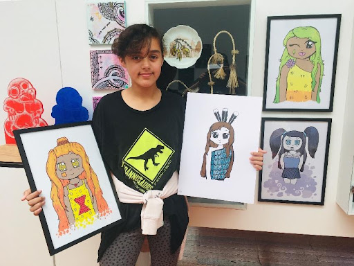 Young female artist standing in from of artwork, holding artwork