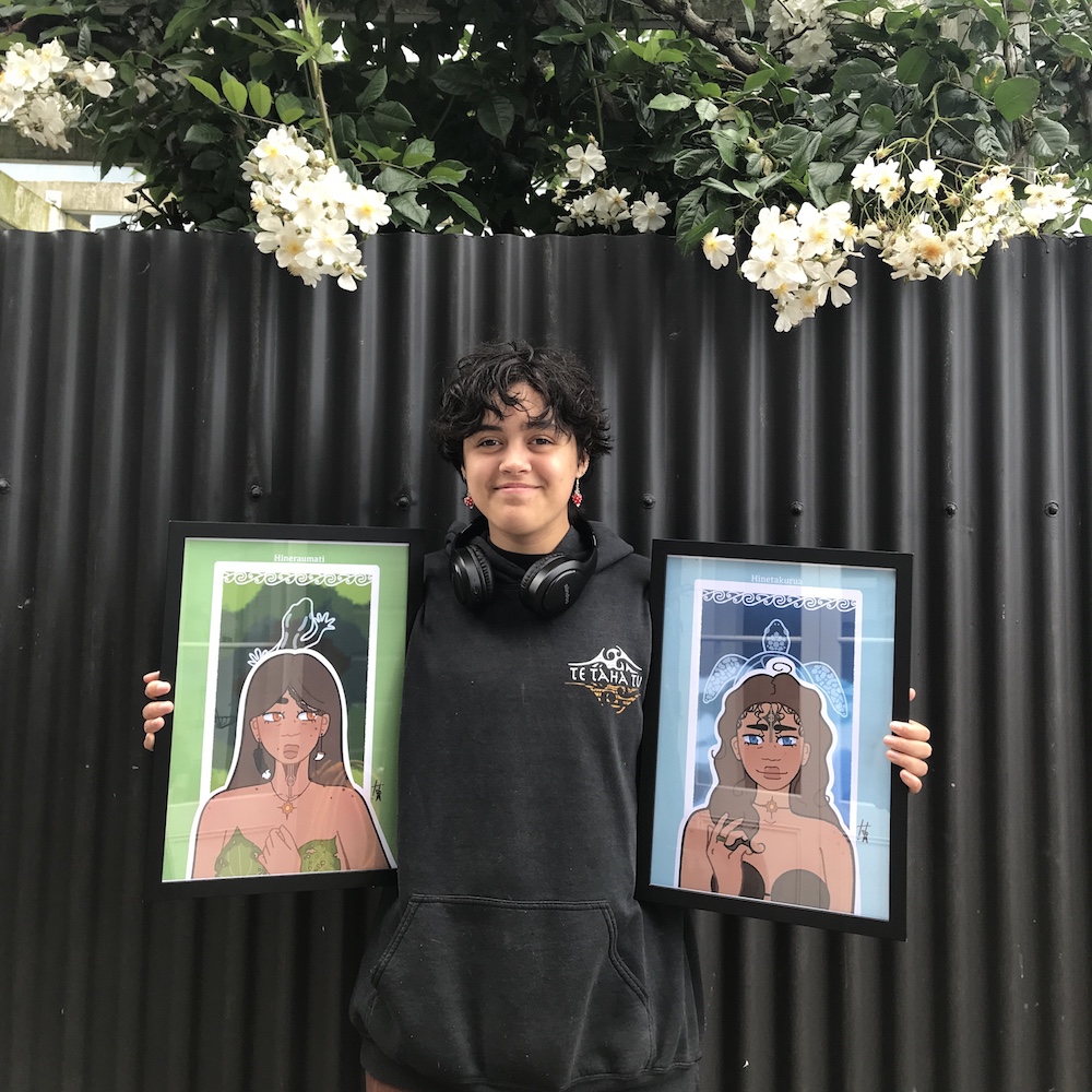 Young male artist standing in from of artwork, holding artwork